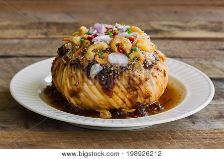 Santol salad on white plate. Spicy and sweet santol salad with Thai style salad dressing topping with dried coconut dried shrimp onion and chili. Delicious slice santol served with sweet and spicy sauce for appetizer or snack on wood table.