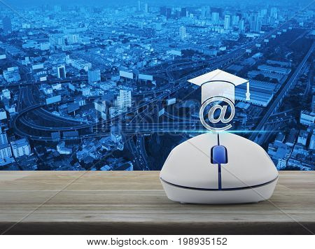 e-learning icon with wireless computer mouse on wooden table over city tower street and expressway Study online concept