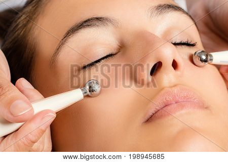 Close up portrait of woman having Galvanic facial treatment with low level current electrodes.