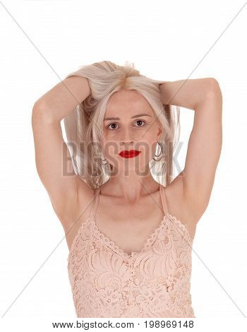 A beautiful young woman standing from the front with her both hands under her blond hair messing up isolated for white background