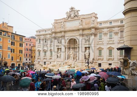 ROME ITALY - OCTOBER 18 2016: Famous Trevi fountain on a rainy day surrounded by lots of tourists with umbrellas