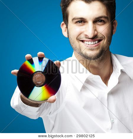 portret przystojny młody mężczyzna trzyma cd na niebieskim tle