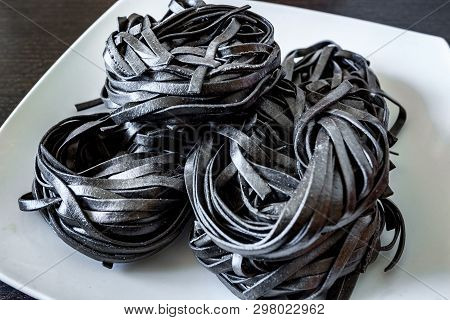 Dry Black Pasta With Cuttlefish Ink. Pasta Of Durum Wheat Semolina With Squid Ink On A Square Plate