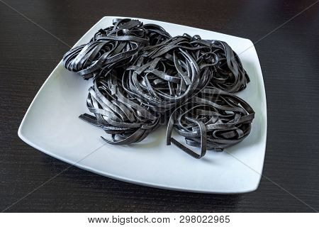 Dry Black Pasta With Cuttlefish Ink. Pasta Of Durum Wheat Semolina With Squid Ink On A Square Plate