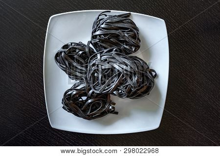 Dry Black Pasta With Cuttlefish Ink. Pasta Of Durum Wheat Semolina With Squid Ink On A Square Plate