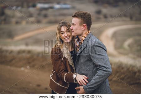 Beautiful Lovely Couple In The Park Or Field Or Track. Man In Coat And Scarf With Girl In Coat. Man 