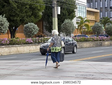 Bayamon/puerto Rico - February 26, 2019: Elderly Woman Crosses Street With Umbrella.