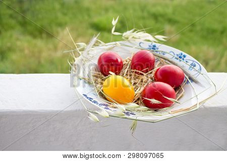 Easter Red And Yellow Eggs With Hay In The Plate On Balkony