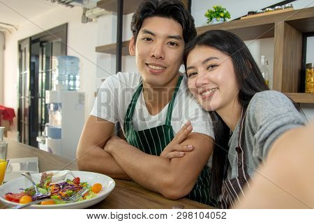 Portrait Of Cute Happy Couple In Aporn In Selfie Action Posting With Mobile Phone Decorated With Sal