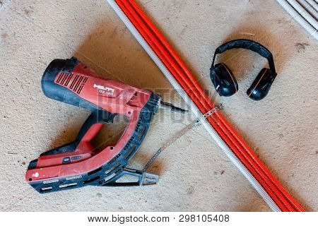 Hilti Nail Gun Next To Headphones And A Nail-mounted Tie