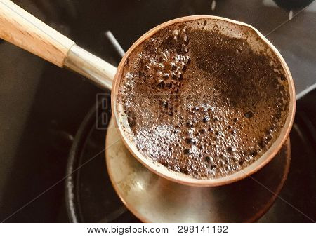Barista Preparing Hot Tasty Drink From Copper Turk, Boils Water For Coffee On Small Fire In Cezve. C