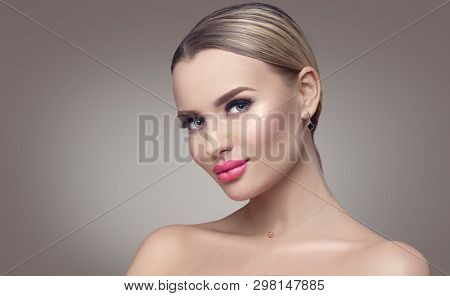 Beauty Woman face Portrait. Beautiful Spa model Girl with Perfect Fresh Clean Skin. Blonde female looking at camera and smiling. Youth and Skin Care Concept. Gray background. Plastic surgery. Fillers