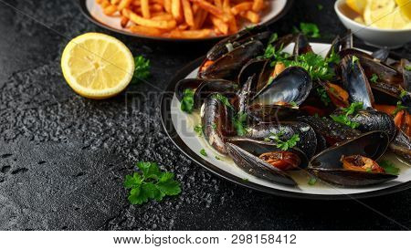 Mussels With White Wine, Garlic, Lemon And Herbs In A Plate, French Fries. Rustick Background. Seafo