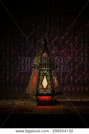 A decorative, dimly lit Ramadan lantern on dark background. Beautiful Egyptian vintage fanous photo from front angle.