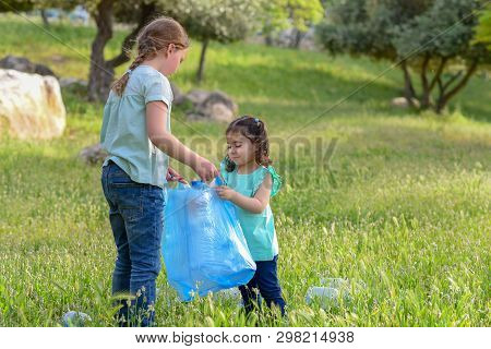 Plastic Pollution On Land. Polluted Park, Environmental Rubish. Children Volunteers With Garbage Bag