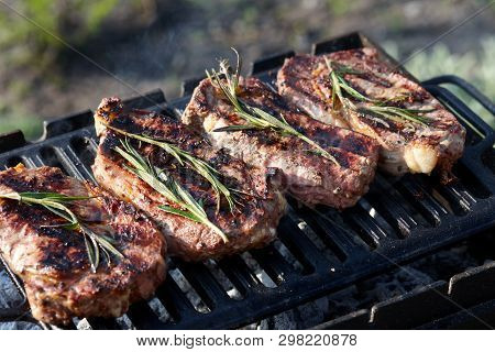 Cooking Outdoors. Juicy Beef Steaks With Rosmary On Grill.