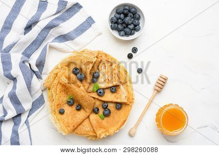 Crepes Or Blini With Fresh Berries And Honey On White Background. Table Top View With Copy Space
