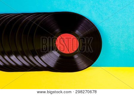 Many Black Colored Vinyl Discks Placed  In A  Line On Yellow And Blue Background.