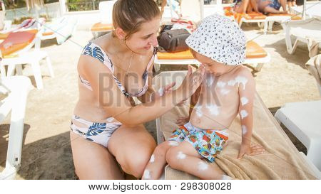 Image Of Young Caring Mother Applying Sunscreen On Her Child To Protect From Harmful Uv Light On Bea