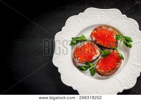 Red Caviar On Black Bread With Butter. Healthy Food. Fish Appetizer. Dark Background
