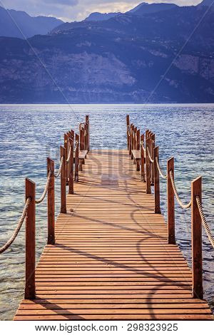 Summer Holiday: Wooden Dock Pier Over Blue Lake Water. Cloudy Evening Scenery.