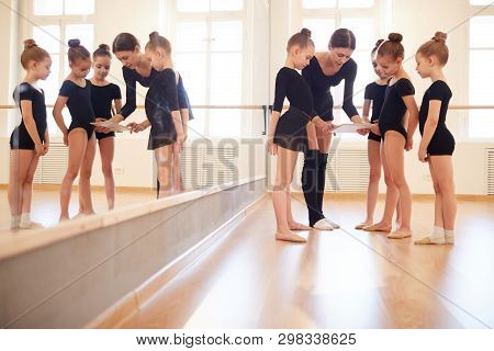 Full Length View At Group Of Little Girls Watching Videos Via Digital Tablet During Dance Practice I