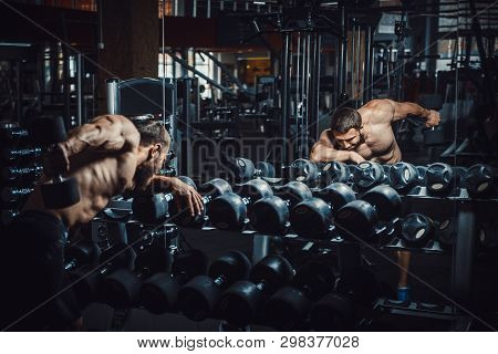 Good Looking Young Man Bodybuilder Doing Triceps Kickback Lifting Dumbbells In Front Of The Mirror L