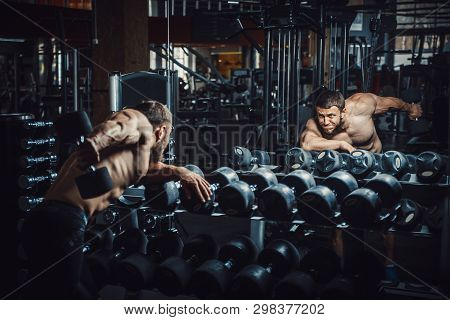 Good Looking Young Man Bodybuilder Doing Triceps Kickback Lifting Dumbbells In Front Of The Mirror L