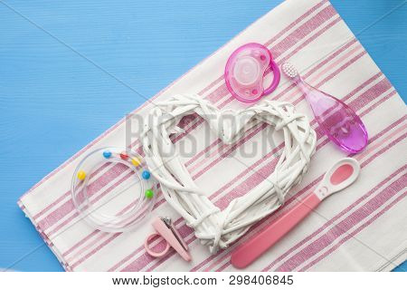 Newborn Baby Story. Strow Heart And Childrens Toys, Scissors, Baby Bottle, Nipple, Hairbrush On Blue