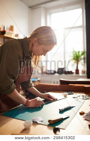 Warm Toned Portrait Of Female Artisan Making Leather Bag In Leatherworking Atelier Lit By Sunlight, 