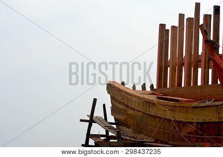 The Wooden Framework Of An Unfinished Boat Is Seen Against An Overcast Sky. Vertical Wooden Beams Ri