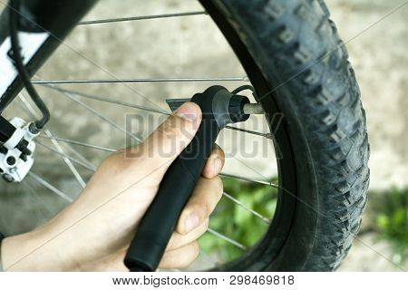 Hand Pump. Guy Shakes A Flat Tire From A Mountain Bike. Bicycle Wheel Close-up