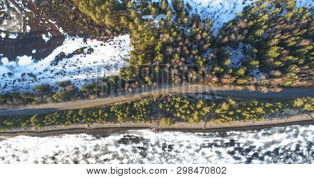 Aerial View Of Spring Rural Road In Yellow Pine Forest With Melting Ice Lake