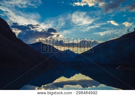 Amazing Blue Silhouettes Of Mountains On Sunset. Vivid Dawn Sky Reflected In Mountain Lake. Wonderfu