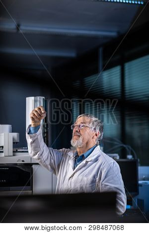 Senior scientist in a chemistry lab carrying out research - looking at gas chromatography samples, preparing the analysis on a modern gas chromatographer  