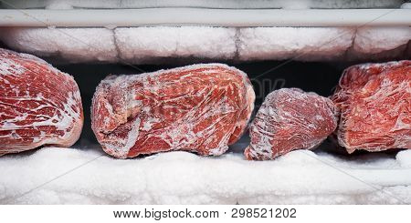 Large Pieces Of Red Meat In A Freezer With A Big Quantity Of Frozen Ice And Snow