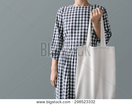 Eco-friendly product Zero waste concept A woman in a plaid cotton dress is holding a reusable white shopping bag