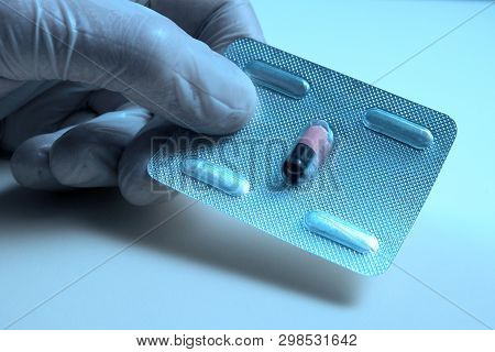 A Hand In A White Medical Glove Delivers A Blister With One Pill For All Ills. Close-up. Medical Con