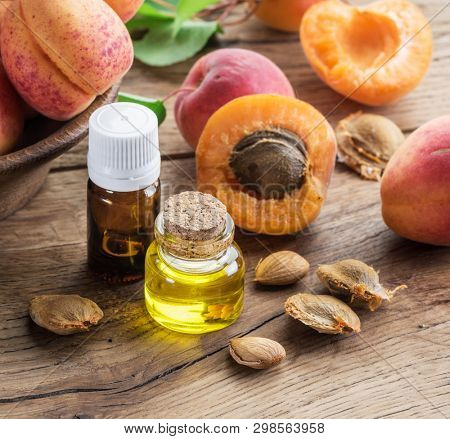 Apricot kernel oil and apricot kernels on wooden background.