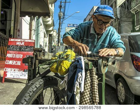 Sao Paulo, Brazil, June 09, 2006: Old Man Works As A Walking Grinder Of Knives And Scissors On The S