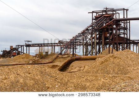 Rusty Pipe On The River Bank, From Which Sewage Flows, Dirty Sand Slurry, And Stationary Rusty Gravi