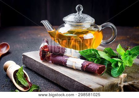 Hot Herbal Tea In A Tea Pot, Leaves Fresh Mint, Dry Fruits Leather Roll And Dry Mint Leaves With Str