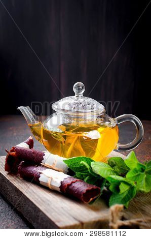 Hot Herbal Tea In A Tea Pot, Leaves Fresh Mint, Dry Fruits Leather Roll And Dry Mint Leaves With Str