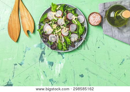 Salad With Radishes, Olive Oil,  Pink Salt, Empty Ceramic Bowl, Wooden Spoons For Salad Over Green C