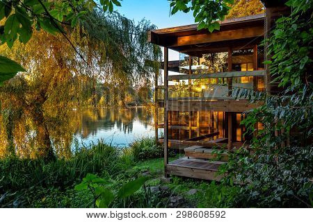 Lonely Small House In The Forest By The Lake. Relaxing Scene,  The House And Trees Are Beautifully R