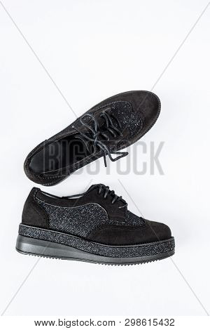 A Pair Of Black Shoes With Shiny Inserts On Thick Soles On A White Background