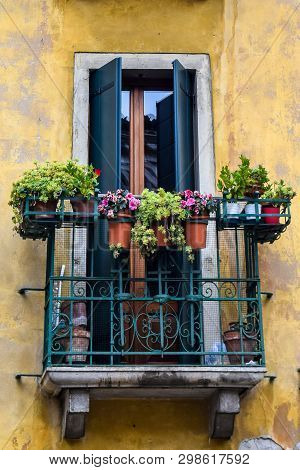 Traditional Italian Balcony Window Of A Home Or Hotel In Venice With Burglar Bars, Potted Flowers/pl