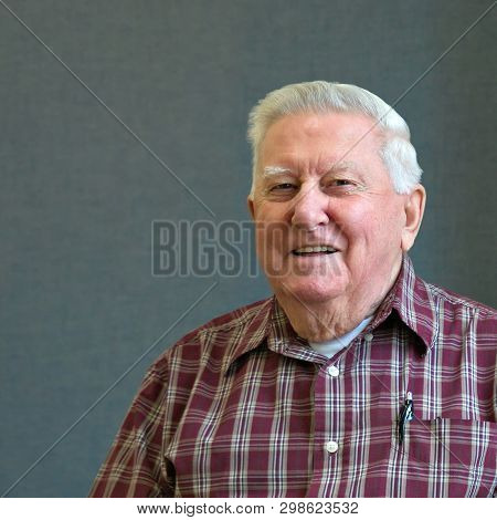 Senior Octogenarian Old Man In Plaid Shirt With Gray Background.