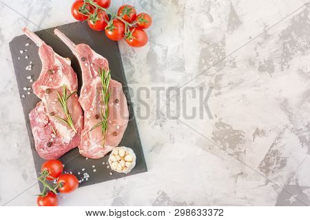Two Piece Raw Meat On Cutting Board With Spice. Uncooked Fresh Pork Bone Steak With Garlic, Tomato A