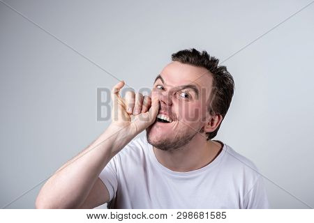 Handsome Brunette Guy With Bristles In A White T-shirt Picks His Finger In His Nose